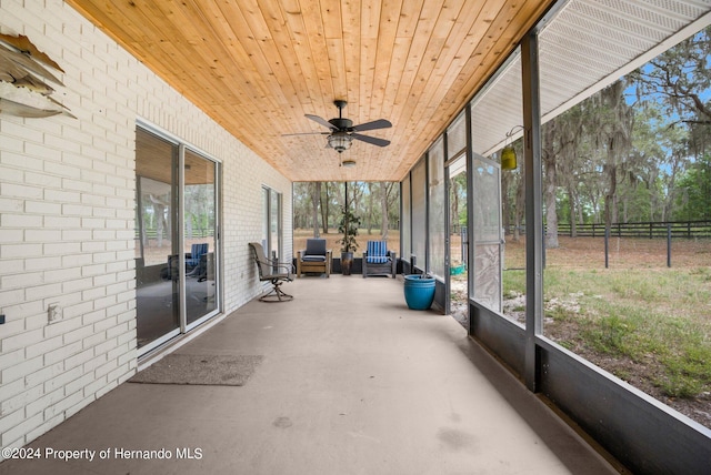 unfurnished sunroom with ceiling fan, a healthy amount of sunlight, and wood ceiling