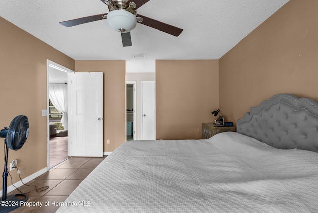 bedroom featuring ceiling fan, a textured ceiling, and light tile patterned floors