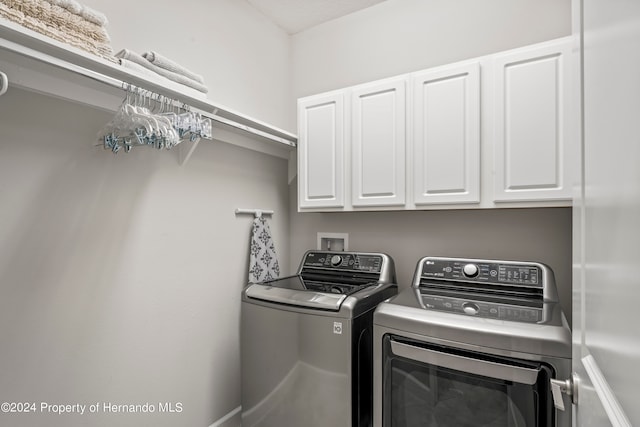 clothes washing area with washing machine and clothes dryer and cabinets