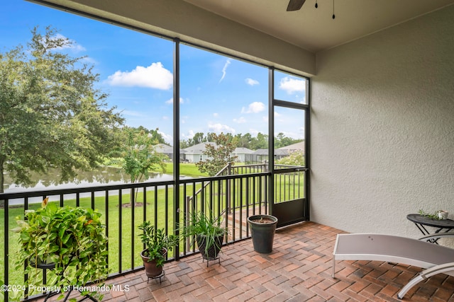 sunroom / solarium with ceiling fan and a water view