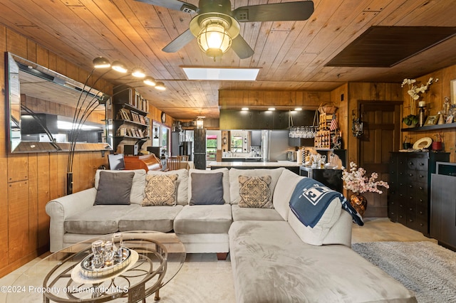 living room with wooden ceiling, ceiling fan, wooden walls, and a skylight