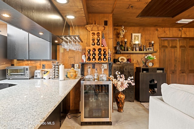 kitchen featuring wooden ceiling, light stone countertops, wooden walls, and beverage cooler