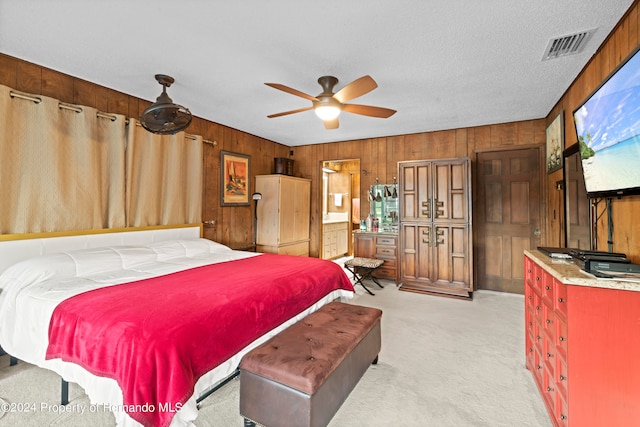 bedroom featuring a textured ceiling, wood walls, ceiling fan, and light carpet