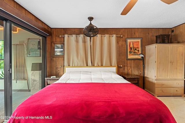 carpeted bedroom with ceiling fan, wooden walls, and access to outside