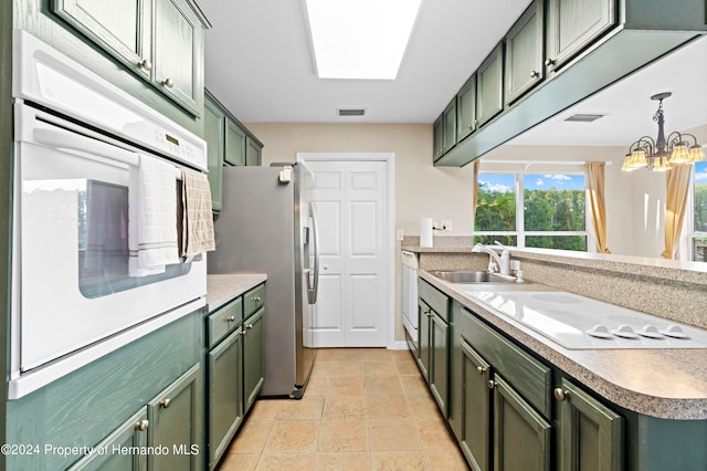 kitchen with pendant lighting, white appliances, sink, and green cabinetry