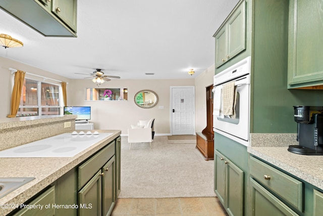 kitchen featuring green cabinetry, light carpet, and oven