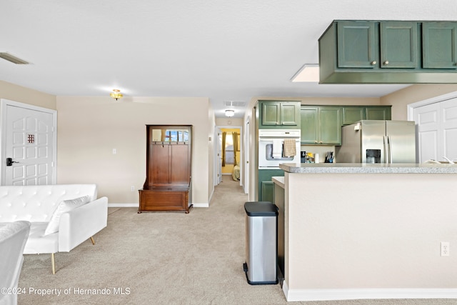 kitchen with white oven, stainless steel fridge with ice dispenser, light carpet, and green cabinets