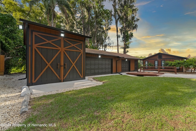 yard at dusk featuring a garage and an outdoor structure