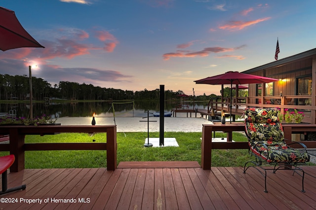 deck at dusk with a lawn and a water view