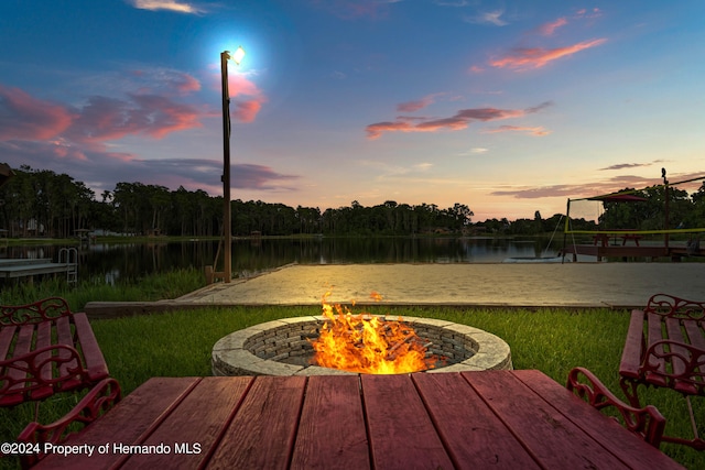 yard at dusk featuring a water view and a fire pit