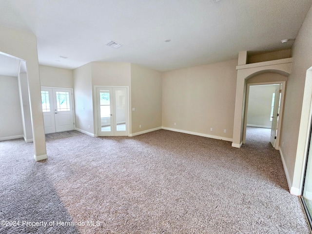 carpeted spare room featuring french doors