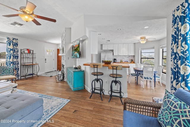 living room with hardwood / wood-style floors, vaulted ceiling, ceiling fan, and a textured ceiling