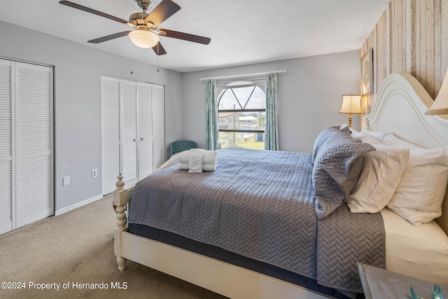 carpeted bedroom with ceiling fan and two closets