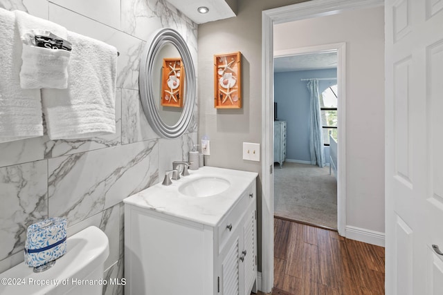 bathroom featuring tile walls, hardwood / wood-style floors, vanity, and toilet