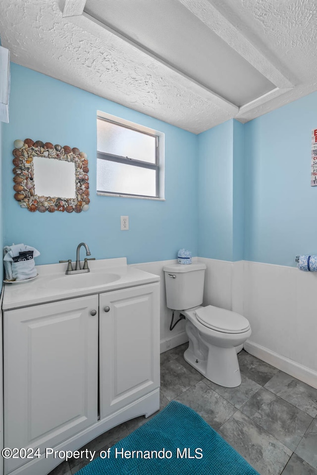 bathroom with vanity, toilet, and a textured ceiling