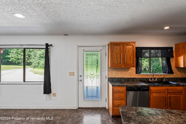 kitchen with a textured ceiling, stainless steel dishwasher, sink, and backsplash