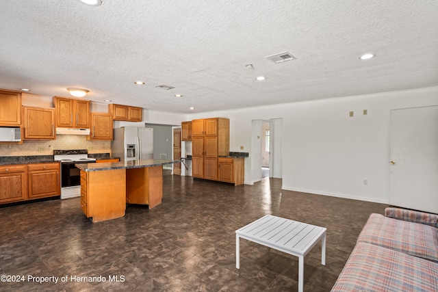 kitchen with a kitchen island, white appliances, a textured ceiling, and a kitchen bar