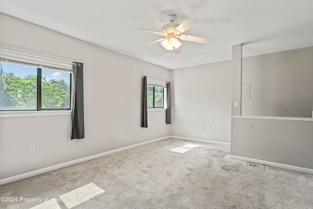 unfurnished room with a wealth of natural light, light carpet, and ceiling fan