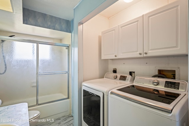 laundry room with a textured ceiling, cabinets, and independent washer and dryer