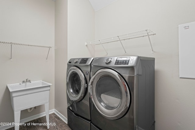 clothes washing area with washing machine and clothes dryer, sink, and dark hardwood / wood-style floors