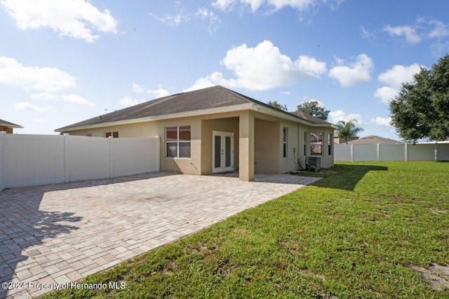 rear view of property featuring french doors, a yard, and a patio area