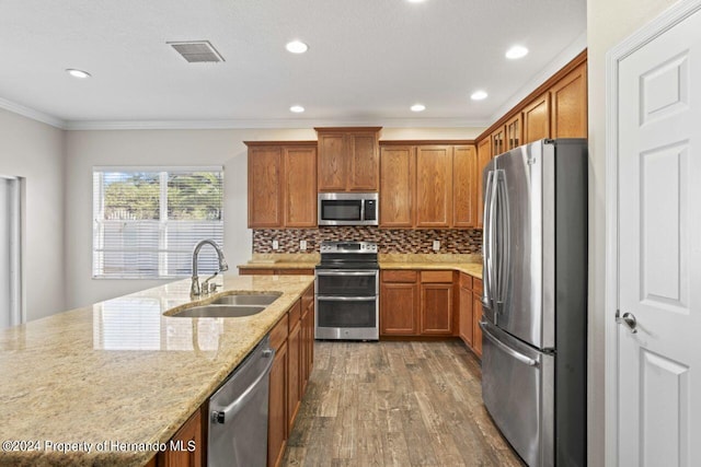 kitchen featuring light stone countertops, appliances with stainless steel finishes, ornamental molding, sink, and dark hardwood / wood-style floors