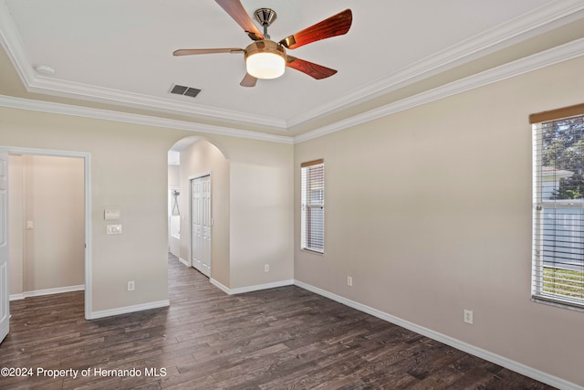 unfurnished room with a tray ceiling, crown molding, ceiling fan, and dark wood-type flooring