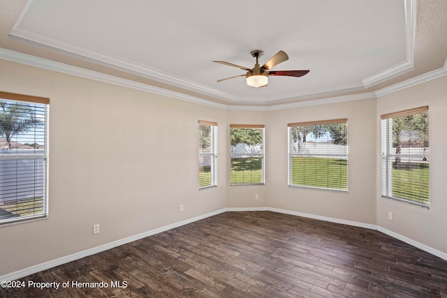 spare room with a tray ceiling, crown molding, ceiling fan, and dark wood-type flooring