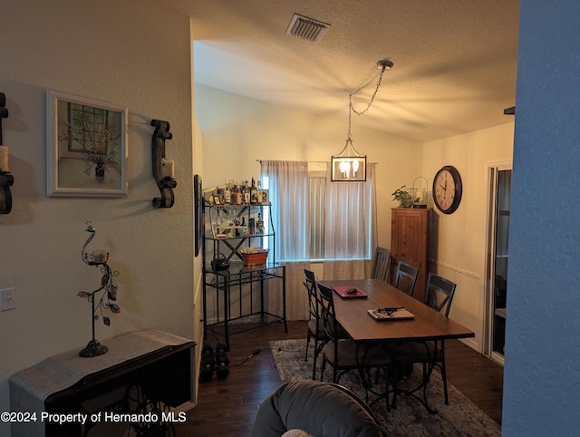 dining area featuring a textured ceiling, lofted ceiling, and dark hardwood / wood-style floors