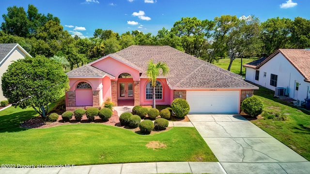 view of front of home featuring a front lawn, a garage, and central AC