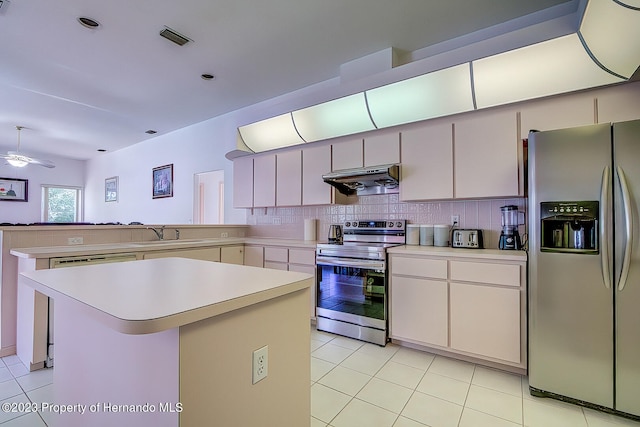 kitchen with backsplash, appliances with stainless steel finishes, light tile patterned floors, sink, and a center island