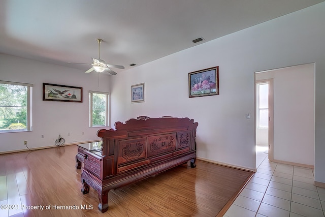 bedroom with ceiling fan, multiple windows, and light hardwood / wood-style flooring