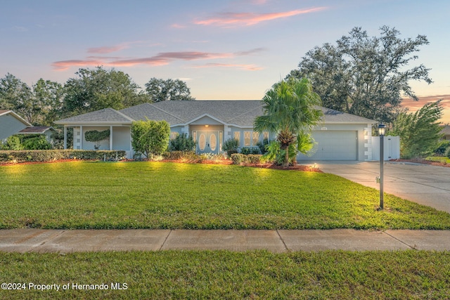 single story home with a garage and a lawn