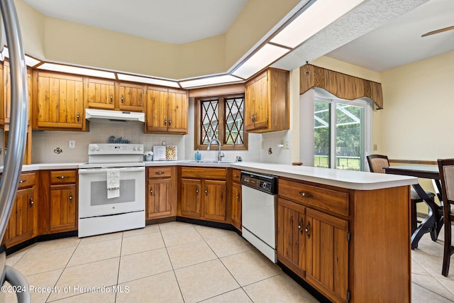 kitchen with kitchen peninsula, sink, light tile patterned floors, backsplash, and white appliances