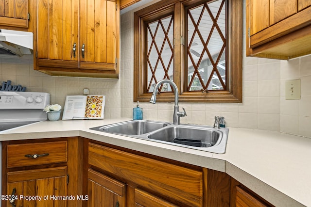 kitchen featuring sink, tasteful backsplash, and white stove