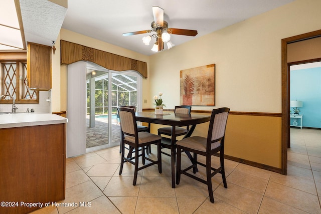 dining area with sink, light tile patterned floors, and ceiling fan