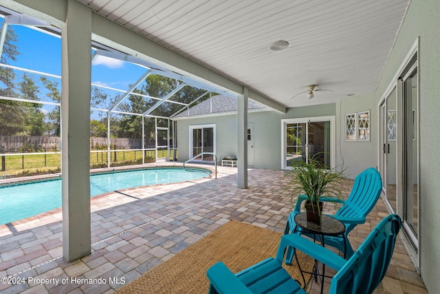 view of pool with glass enclosure, a patio area, and ceiling fan