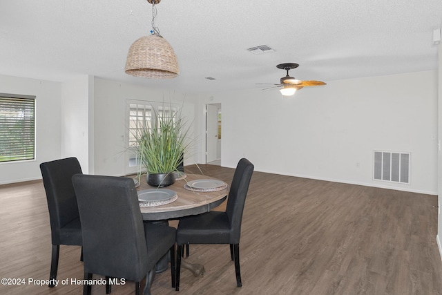 dining room featuring ceiling fan, dark wood-type flooring, and a textured ceiling