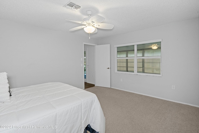 bedroom with ceiling fan, a textured ceiling, and carpet floors