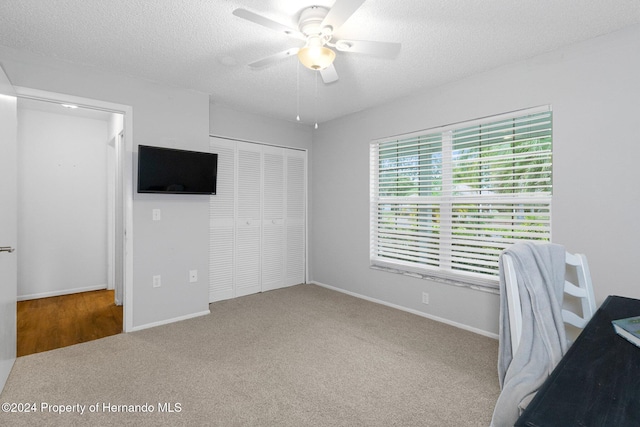 unfurnished office with ceiling fan, a textured ceiling, and carpet flooring