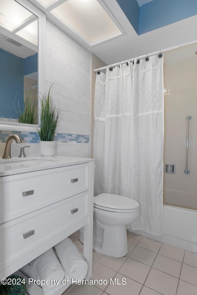 full bathroom featuring tile patterned flooring, vanity, tile walls, toilet, and shower / bath combo with shower curtain