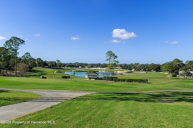 surrounding community with a water view and a lawn