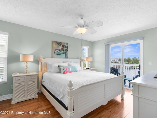 bedroom with access to exterior, hardwood / wood-style floors, a water view, and multiple windows