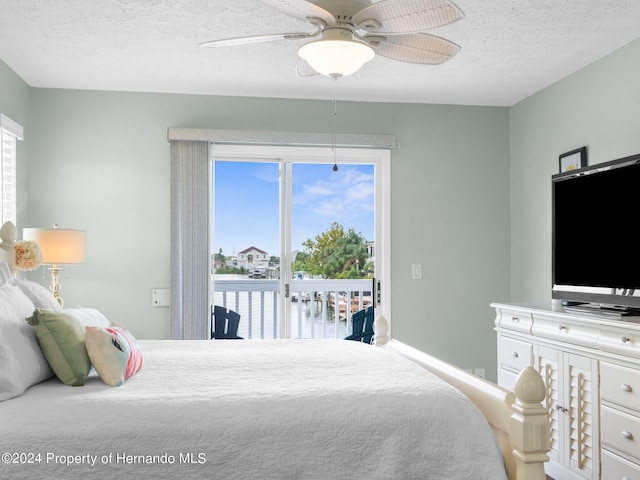 bedroom featuring ceiling fan, access to exterior, and a textured ceiling