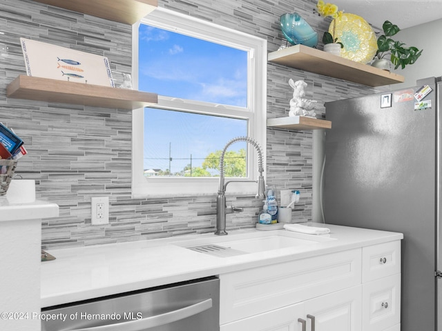 kitchen with white cabinets, decorative backsplash, stainless steel appliances, and sink