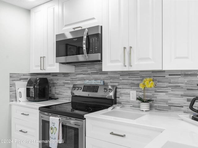 kitchen featuring decorative backsplash, white cabinetry, and appliances with stainless steel finishes