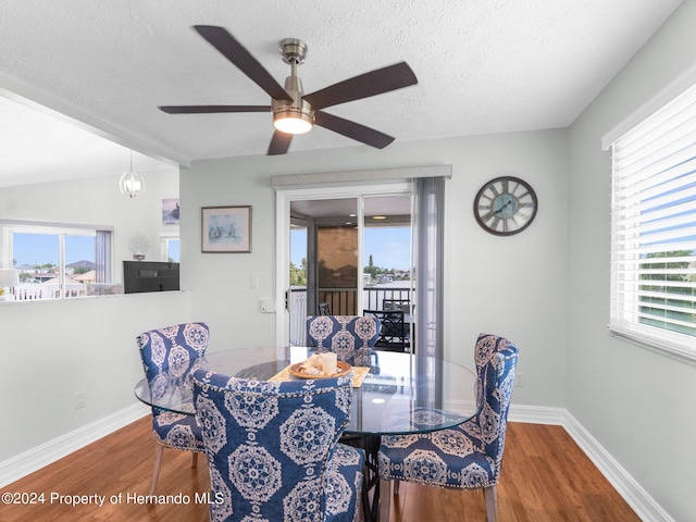 dining space with hardwood / wood-style floors, a textured ceiling, vaulted ceiling, and a healthy amount of sunlight