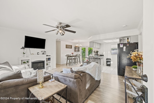 living room with light hardwood / wood-style floors, ceiling fan with notable chandelier, and ornamental molding