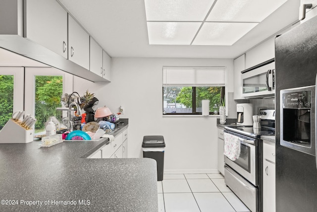 kitchen featuring appliances with stainless steel finishes, light tile patterned floors, and white cabinets