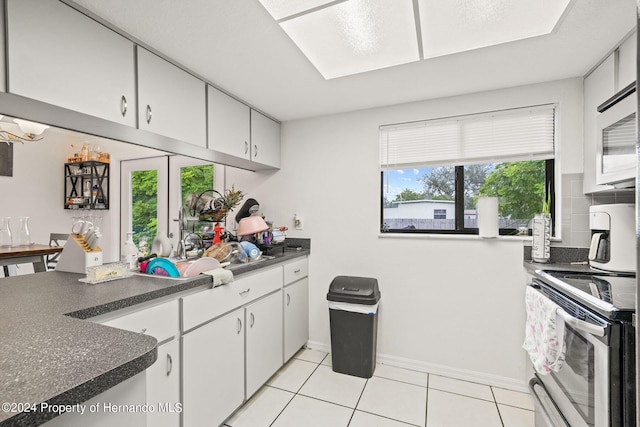 kitchen featuring electric stove, light tile patterned flooring, and white cabinets